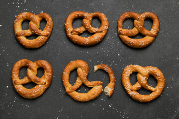 Tasty pretzels with salt on black background, closeup