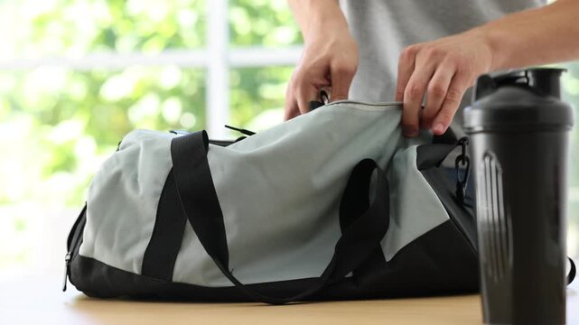 Man packing his sports bag for training at home, closeup