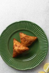 Overhead view of samosa on a green plate, top view of beef samosa on a marble countertop