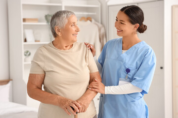 Obraz premium Female caregiver and happy senior woman with walking stick at home