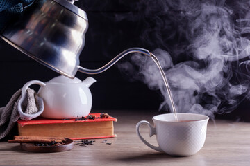 Hot tea is poured into glasses with steam. Teacups are placed on the table in the warm atmosphere of morning sunlight.
