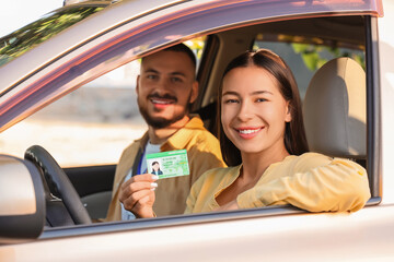 Young woman with instructor passing driving license test in car