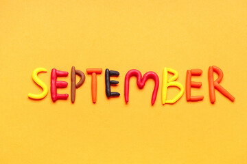 Word SEPTEMBER made of play dough on yellow background