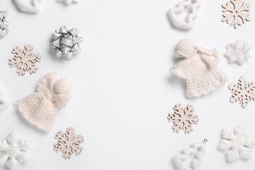 Frame made of decorative snowflakes and knitted angels on white background, closeup