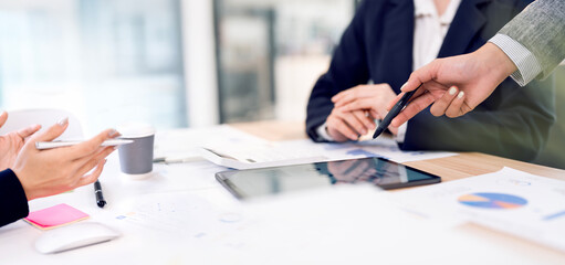 A close-up view of business colleagues collaborating on a project. One person points to a tablet,  business meeting or a team working together on strategy  in a professional office setting.