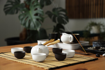 Chinese tea ceremony set with hot beverage in cups on table in room