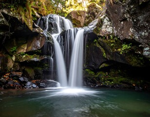A tranquil waterfall cascading over dark rocks into a serene pool