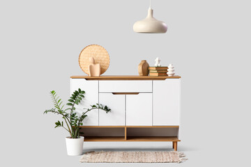 Chest of drawers with books and statuettes on white background