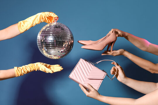 Female hands with disco ball, high heels and bag on blue background