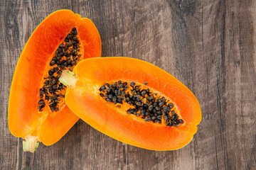 Papaya fruit on a dark wooden background. Slices of sweet papaya on wooden background, Halved papayas, copy space for text