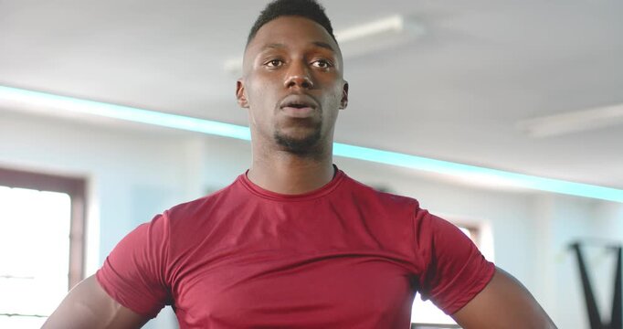 After weight set, African American man breathing hard scanning blue-lit gym while prepping next set