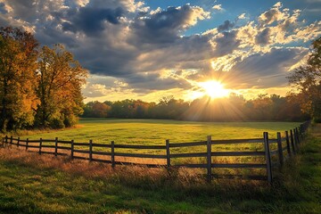 Fototapeta premium Sunburst over Green Field and Wooden Fence During Autumn Scenic Countryside Landscape