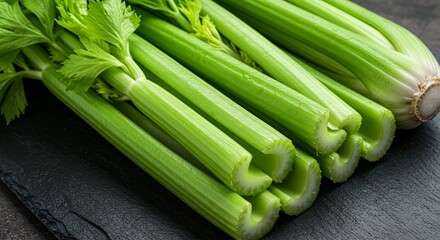 Fresh celery stalks on dark surface, vibrant green, wholesome, healthy, nutritious, ingredient. Perfect for snacking or adding to recipes.