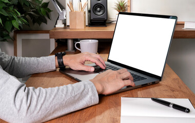 A close-up view of a person working on a modern laptop with a blank, white screen. The image is...