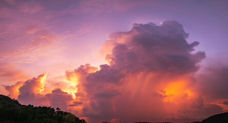 A vivid and dynamic sky captures towering storm clouds illuminated by the warm hues of a setting...