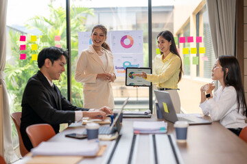 Fototapeta premium Businesswomen showing pie chart on tablet during office meeting