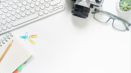 Fototapeta premium Clean white office desk flatlay with modern keyboard, vintage camera, eyeglasses and succulent for creative workspace and productivity vibes