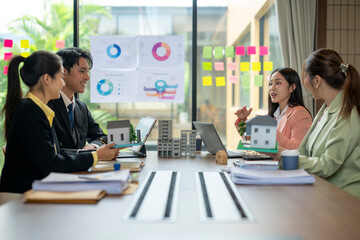Real estate agents discussing housing project with miniature models in office meeting