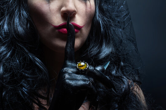 Close up photo of mexican witch or sorceress showing a silence gesture (Shh Gesture). Halloween concept.