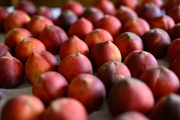 Beautiful tasty fresh peaches laying out on a table with bright red, orange and peach colors.
