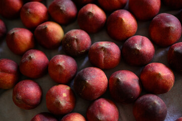 Beautiful tasty fresh peaches laying out on a table with bright red, orange and peach colors.