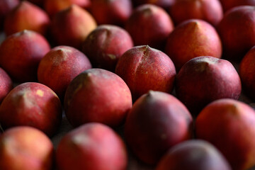 Beautiful tasty fresh peaches laying out on a table with bright red, orange and peach colors.
