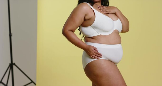 Prompted by cue, female model shifting, rotating and posing to showcase bra against studio backdrop
