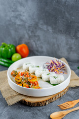 Balinese spicy fish served with rice and vegetables, topped with vibrant chili and spice salsa. This dish bursts with aromatic herbs and authentic island flavors.