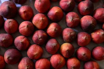 Beautiful tasty fresh peaches laying out on a table with bright red, orange and peach colors.