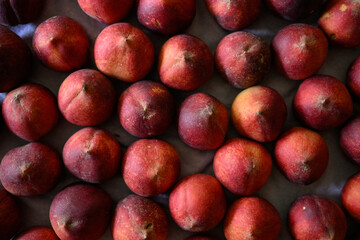 Beautiful tasty fresh peaches laying out on a table with bright red, orange and peach colors.