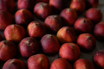 Beautiful tasty fresh peaches laying out on a table with bright red, orange and peach colors.