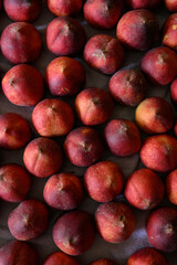 Beautiful tasty fresh peaches laying out on a table with bright red, orange and peach colors.