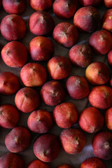 Beautiful tasty fresh peaches laying out on a table with bright red, orange and peach colors.
