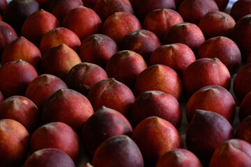 Beautiful tasty fresh peaches laying out on a table with bright red, orange and peach colors.