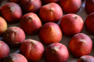 Beautiful tasty fresh peaches laying out on a table with bright red, orange and peach colors.