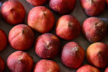 Beautiful tasty fresh peaches laying out on a table with bright red, orange and peach colors.