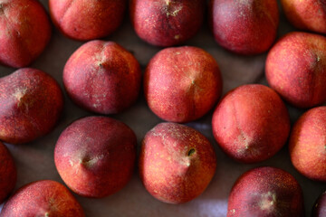 Beautiful tasty fresh peaches laying out on a table with bright red, orange and peach colors.