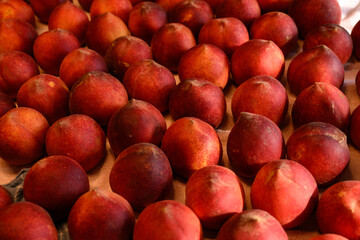 Beautiful tasty fresh peaches laying out on a table with bright red, orange and peach colors.