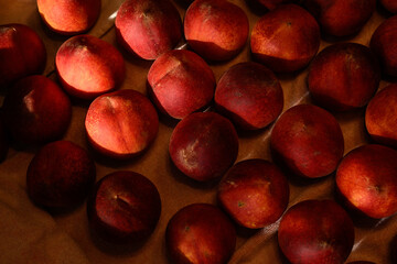 Beautiful tasty fresh peaches laying out on a table with bright red, orange and peach colors.