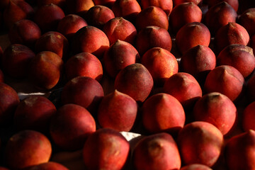 Beautiful tasty fresh peaches laying out on a table with bright red, orange and peach colors.