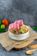 Soto Padang is a classic Minang beef soup with clear broth, fried crunchy beef, vermicelli, potato croquette, and pink sago crackers. Its rich spices and fresh toppings create a flavorful, vibrant bow
