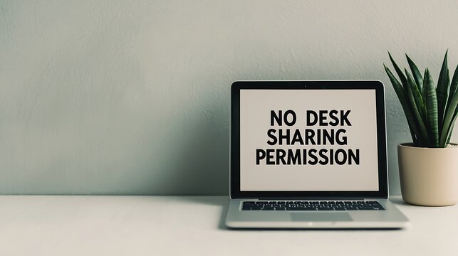 A laptop on a desk displays a bold message, "NO DESK SHARING PERMISSION," next to a potted plant, emphasizing personal workspace boundaries.