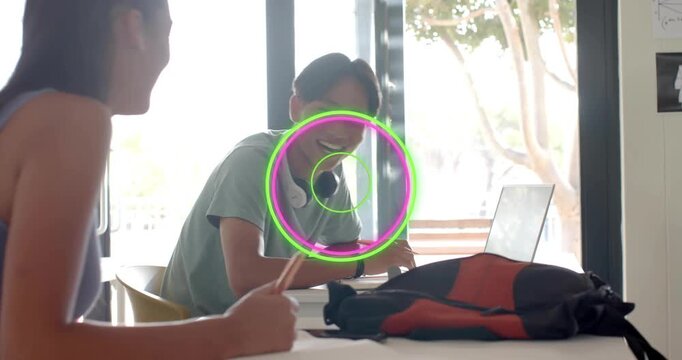 Teenage students writing notes laughing after boy raising pencil refocusing during study session
