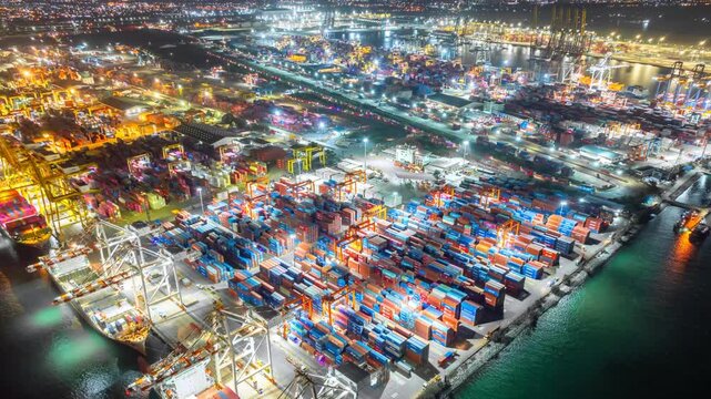Aerial view hyperlapse container cargo ship international port terminal with gantry crane at night, Industrial cargo container port loading and unloading, Global business logistic import export.