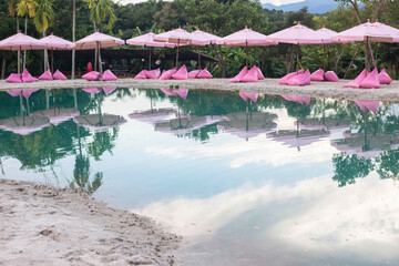 Pink umbrellas on the artificial sea behind are beautiful green mountains