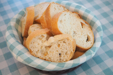 Fresh bread slices in a woven basket on a checkered table