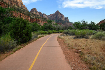 Recreational asphalt path in Zion National Park leading towards The Watchman geologic feature mountain peak, outdoor recreation, arid desert climate
