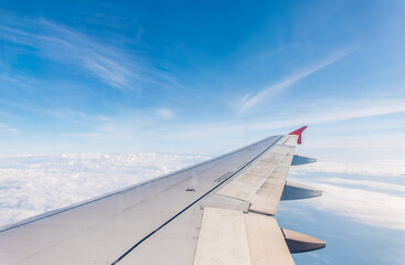 Fototapeta premium View from the airplane window at a beautiful cloudy sky and the airplane wing