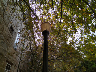 Old street lamppost by a stone building	, braga, portugal