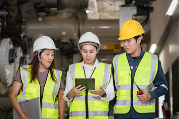teamwork and industrial safety, Group of engineers and technicians wearing safety helmets and reflective vests inspecting high-voltage gas-insulated switchgear (GIS) inside a power plant